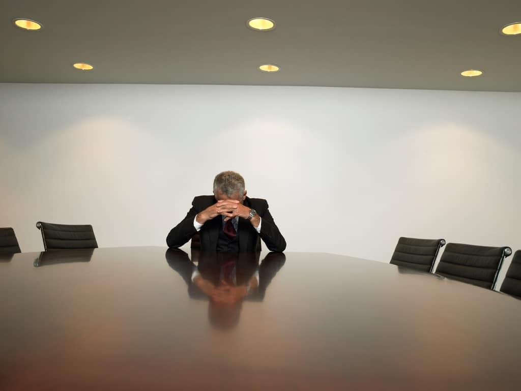 Businessman sitting alone at a long boardroom table
