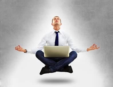 Businessman meditating with a laptop