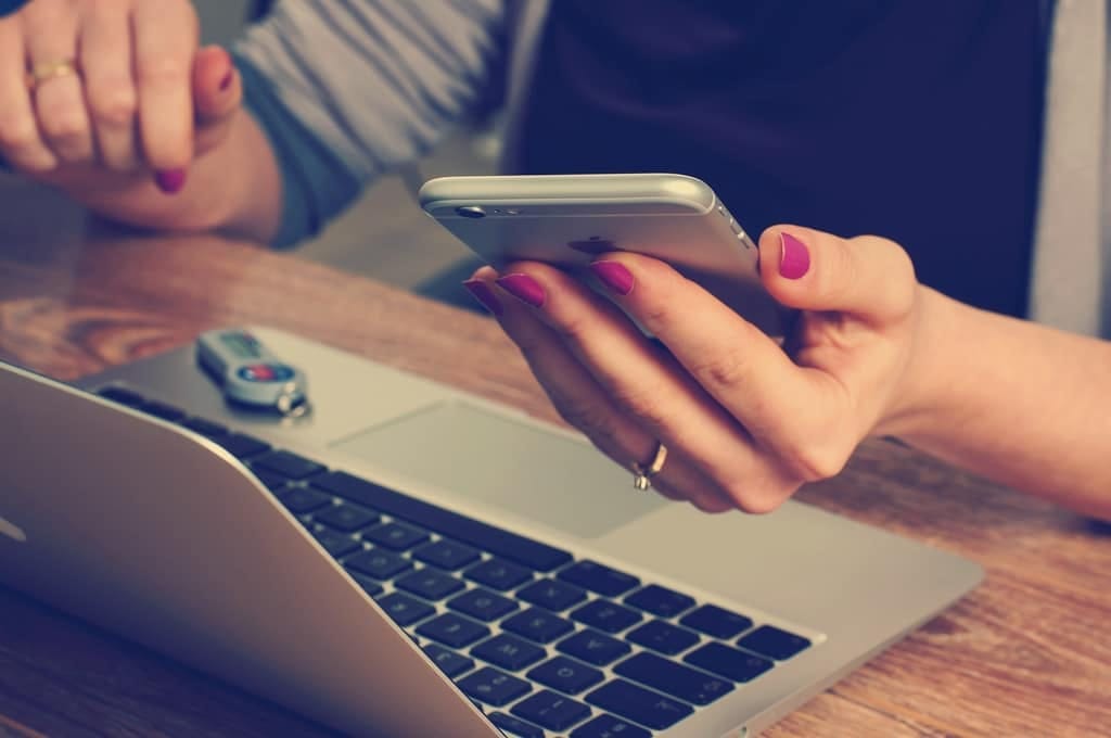Hands holding a phone over a laptop for an online session