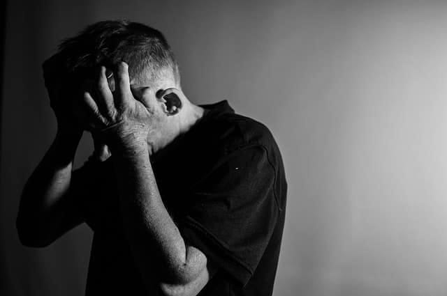 Black and white photo of a man with his head in his hands