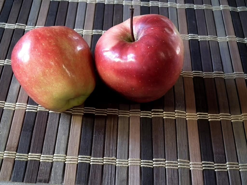 Two red apples on a placemat